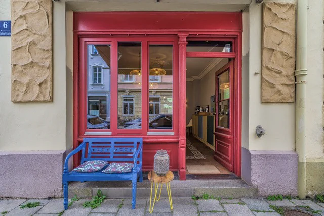 Die rote Ladentür der Concept Kitchen mit blauer Bank davor, Hausnummer 6